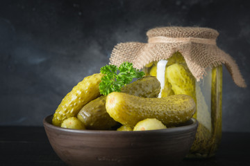Canned vegetables cucumber in bowl on dark wooden board. Close up.