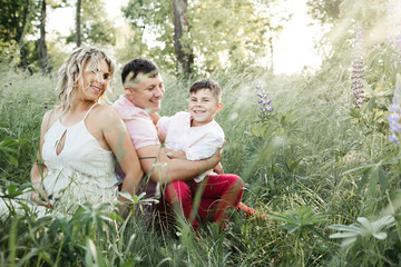 dad with mom look on their son among greenery lawn