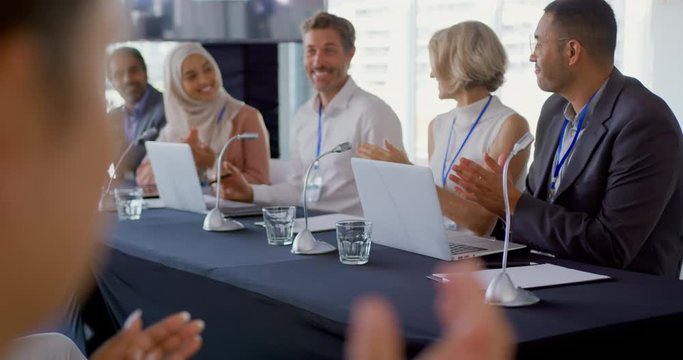 Audience And Panel Of Business Delegates Applauding Businessman At A Conference