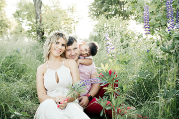 Naklejka premium a young family with their son sit among greenery lawn