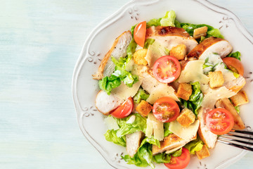 A close-up of a chicken Caesar salad, shot from the top with a place for text