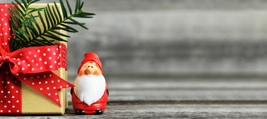Christmas background with copy space. Santa Claus figurine and Christmas gift on wooden background.