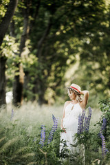 a beautiful pregnant woman stands among greenery lawn