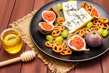 Cheese plate with blue cheese, honey, walnuts, figs, grapes, pretzels