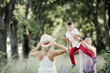 a father has fun with a son, and  a mother holds for her hat