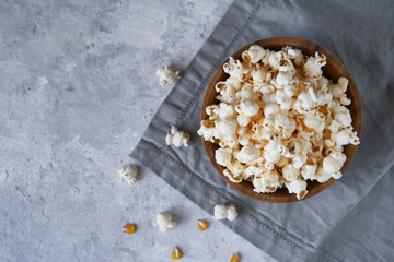 Traditional popcorn in a wooden bowl and corncobs on the table.
