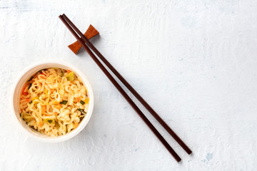 Plastic cup of instant ramen noodles, shot from above with chopsticks and a place for text