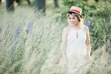 a beautiful pregnant woman stands among greenery lawn