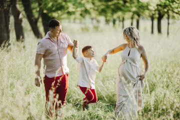 a father with a mother hold a son hands among greenery lawn