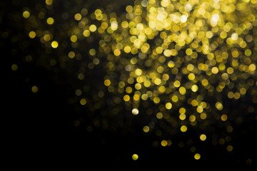 Abstract blurred glitter bokeh background in gold, on black