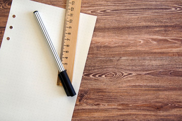 Clear page of dot grid paper with striped black pen and ruler on a wooden table, bullet journal concept. Copy space