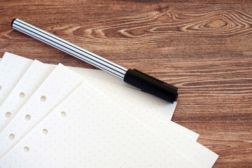 Clear pages of dot grid paper with striped black pen on a wooden table