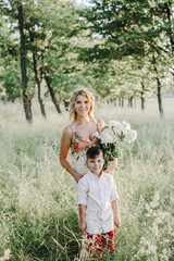 a portrait of a mother with her son among greenery lawn