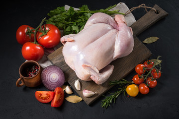 Raw chicken on a wooden board on a black background