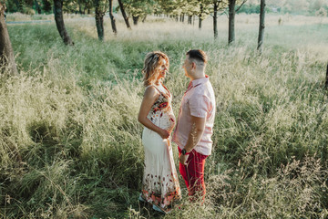 a man looks at his beautiful wife among lawn on sunset