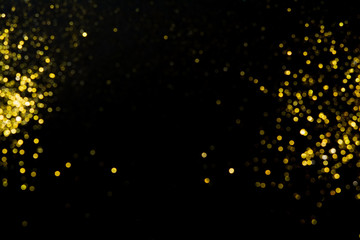 Abstract blurred festive glitter bokeh background in gold, on black