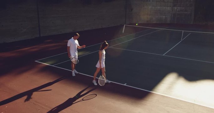 Woman and man playing tennis on a sunny day