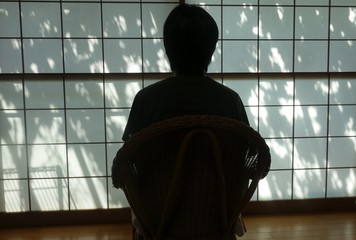 障子の方を向いて椅子に座る人物