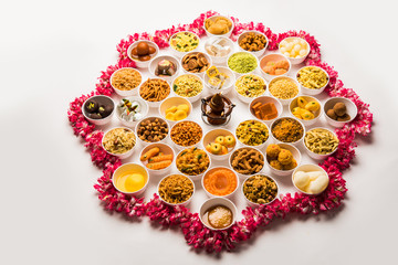Rangoli of sweets and Farsan/snacks in bowls for Diwali with diya over white background
