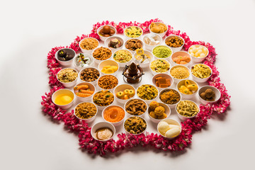 Rangoli of sweets and Farsan/snacks in bowls for Diwali with diya over white background