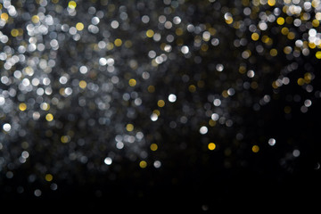 Abstract blurred festive glitter bokeh background in gold and silver, on black