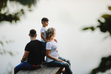parents sit on a bridge and their son stands near