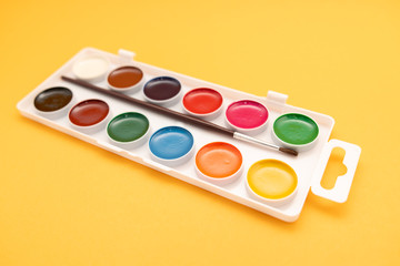 watercolor paints in box on yellow background