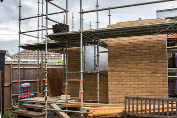 Naklejka premium Renovation projects. Building of extension of the existing house, finished brick walls, scaffoliding, selective focus