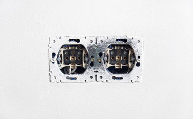 Open electric power sockets on white plaster wall background, repair and mounting