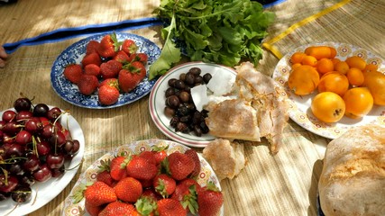 Close-up shot of sweet cherry, ripe strawberry, pickled olives, white bread, cheese, small orange. 4K