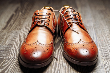 Pair of brown leather men's shoes on the wooden floor.