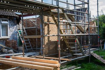 Renovation projects. Building of extension of the existing house, unfinished brick walls, stacks of materials on scaffoliding, selective focus