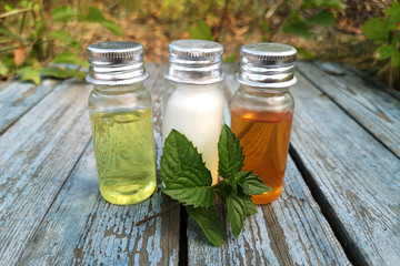 Cosmetic three bottles with white, yellow and orange body butter, against garden maintenance . Background old blue wooden surface. The concept of 