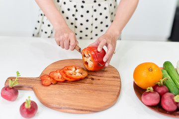 Young woman is chopping vegetables in the kitchen