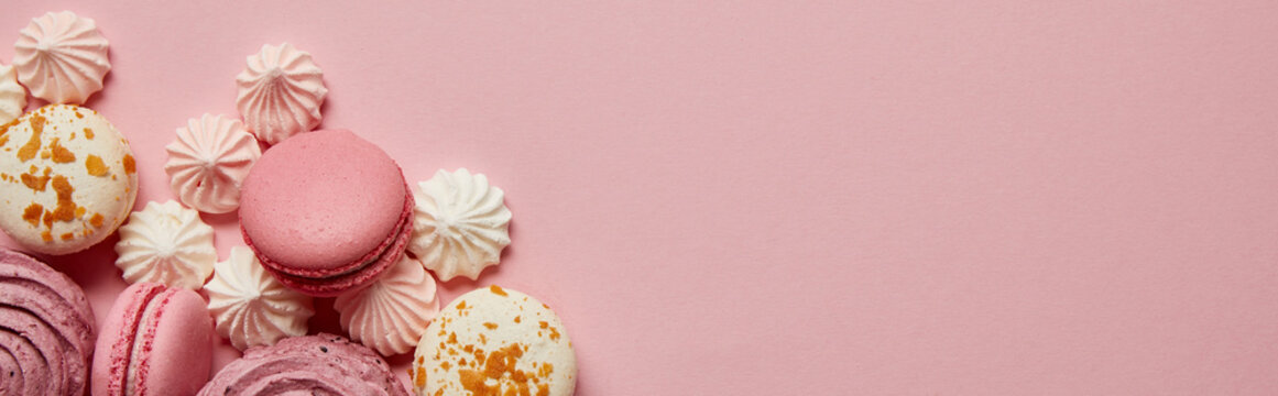 Top view of gourmet pink macaroons, assorted meringues and soft zephyr on pink background