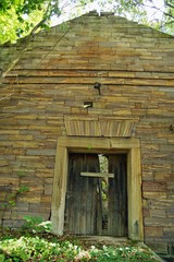 Ruins, old ruined abandoned stone house, empty house facade in a thicket of trees with Boarded up door, installed boards on the door to prevent unauthorized access. solitude, merging with nature. 