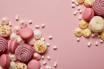 Abwaschbare Fototapete Macarons Zertrümmerte köstliche süße Baiser, Makronen und kleine Marshmallow-Stücke auf rosa Hintergrund