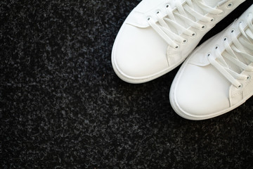 Pair of new stylish white sneakers on floor at home