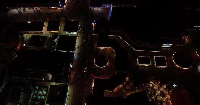 Boardwalk amusement pier aerial video footage from drone at night time bright lights against dark sky