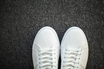 Pair of new stylish white sneakers on floor at home