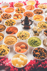Rangoli of sweets and Farsan/snacks in bowls for Diwali with diya over white background