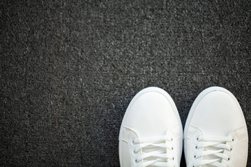 Pair of new stylish white sneakers on floor at home