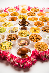 Rangoli of sweets and Farsan/snacks in bowls for Diwali with diya over white background