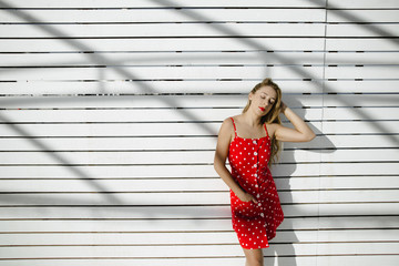 a girl leans to a wall outdoor and squints her eyes