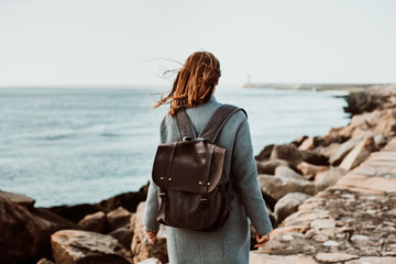 .Pretty young woman with grey coat enjoying a sunny and windy morning around the coast in Porto,...