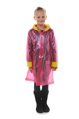 Full shot of a little blonde girl dressed in a cherry-coloured nacre raincoat, black jeans, black top and black high shammy boots. The raincoat with pockets is buttoned with press-studs, 
