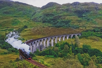 Fototapeta na wymiar Historical steam train passing stone viaduct.