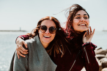.Lesbian couple laughing together on their trip to Porto in Portugal. Walking along the coast on a...