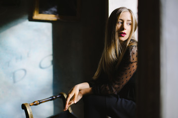 a girl with contemplative look sits on a windowsill