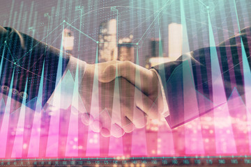 Double exposure of financial graph on cityscape background with two businessman handshake. Concept of stock market deal